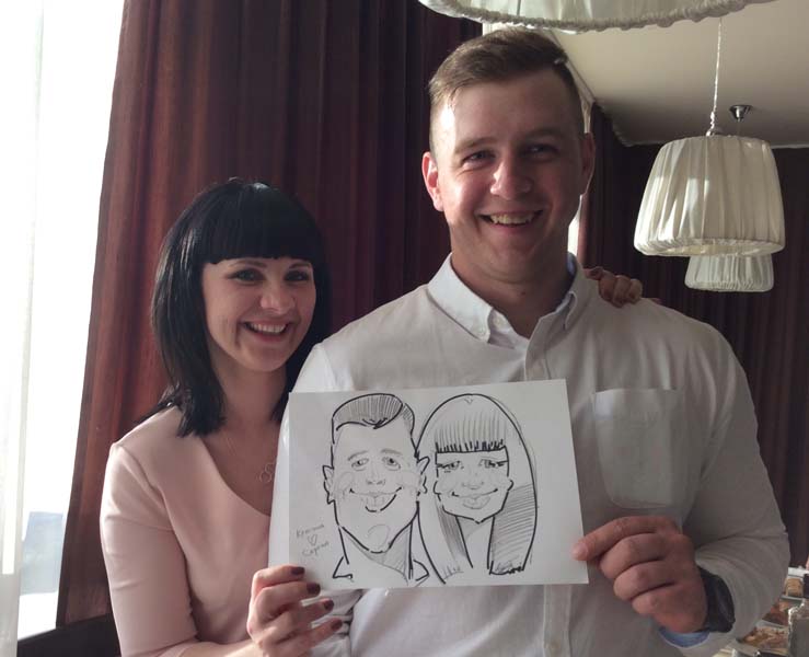 Кристина и Сергей держат свой шарж в ресторане 